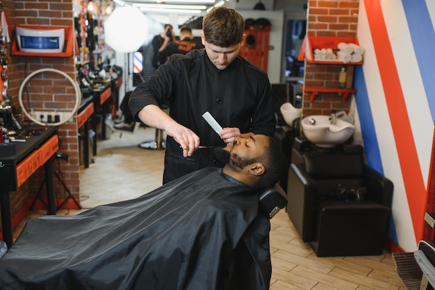 Young African guy getting new haircut in barber salon