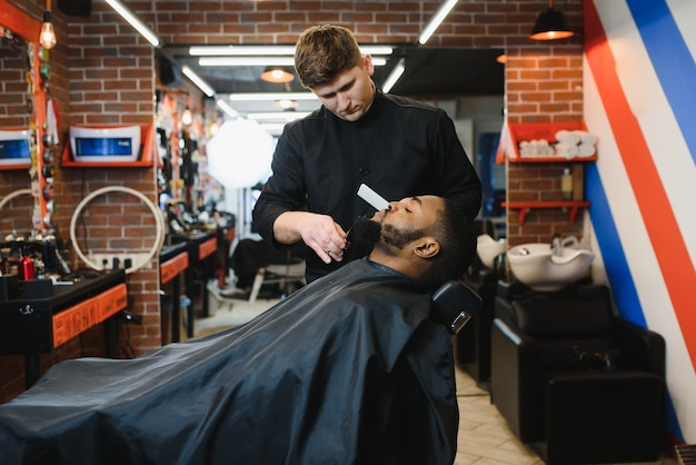 Young African guy getting new haircut in barber salon