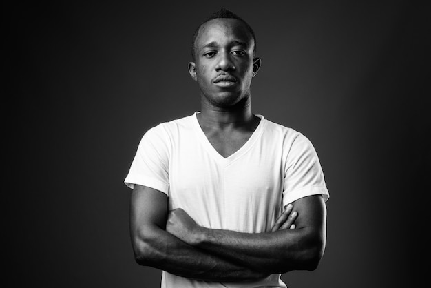 Young African man against black wall in black and white