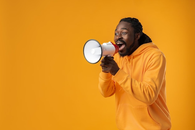 Young african man against yellow background with megaphone