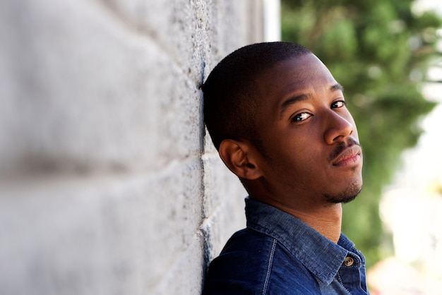 Young african man leaning against wall