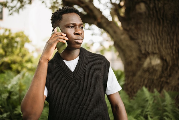 Young African man talking on phone shocked stressed unsatisfied