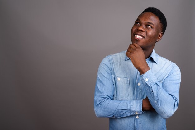 young African man wearing denim shirt against gray space