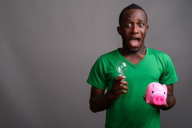 Young African man wearing green shirt on gray wall