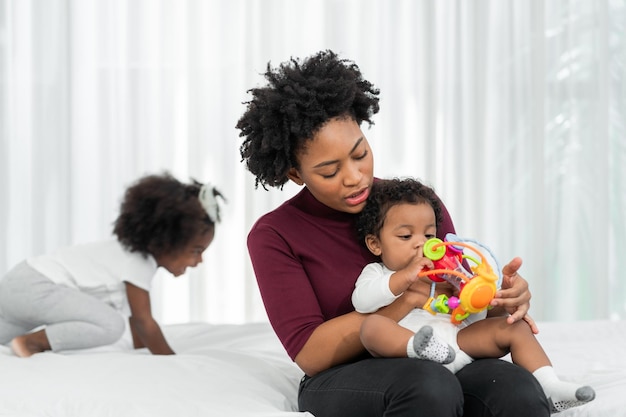 A young African mother raises her children and plays with them lovingly at home