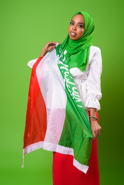 Young African Muslim woman against chroma key with green wall