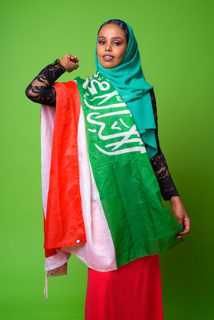 Young African Muslim woman against chroma key with green wall