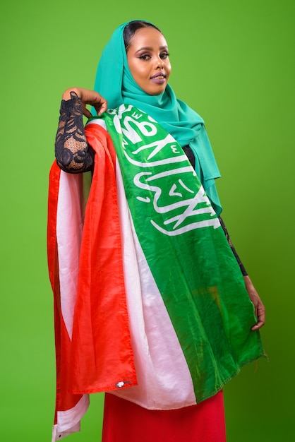 Young African Muslim woman against chroma key with green wall