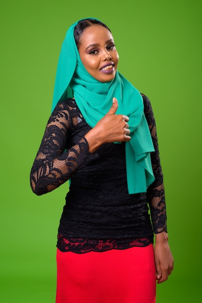 Young African Muslim woman against chroma key with green wall