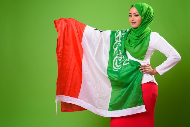 Young African Muslim woman against chroma key with green wall