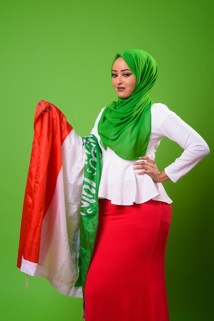 Young African Muslim woman against chroma key with green wall