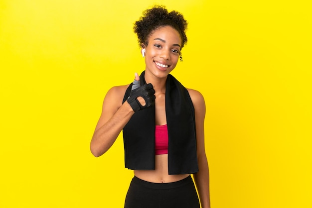 Young African sport woman isolated on yellow background giving a thumbs up gesture