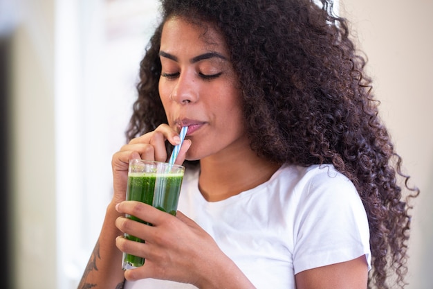 Young african woman enjoy healthy vegetarian smoothie for weight loss and detox  