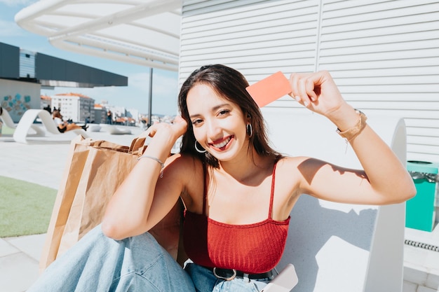 Young african woman holding a credit card blanck space shopping outdoors with copy space. Happy, trendy hipster girl ordering food online, booking tickets during a sunny day. Trendy young people