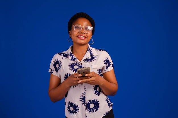 Young african woman isolated on blue background sending a message with the mobile