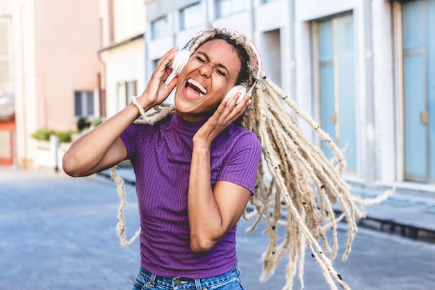 Young african woman listening and dancing to music with headphones - Focus on face