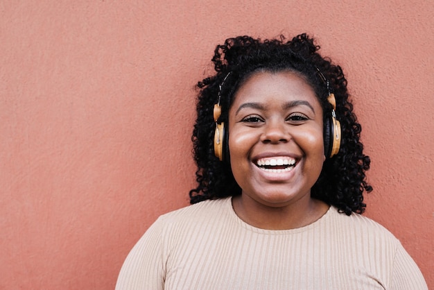 Young african woman listening music with headphones - Focus on face