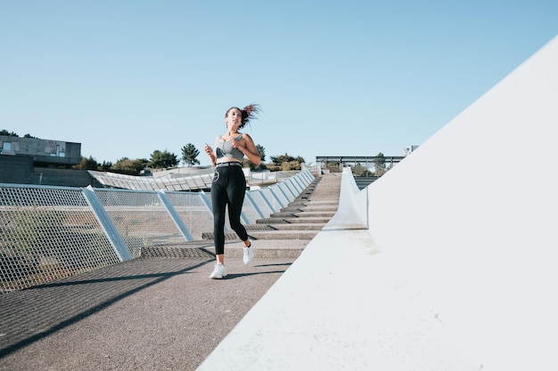 Young african woman running on sport clothes in the city, concrete background, urban sport style, copy space, young athletics