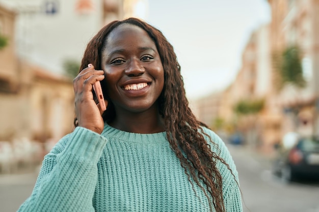 Young african woman smiling happy speaking on the phone at the city