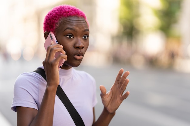 Young african woman talking energetically on her mobile outdoors