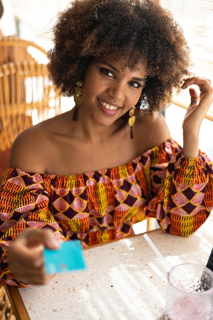 Young African woman with credit card to pay in restaurant