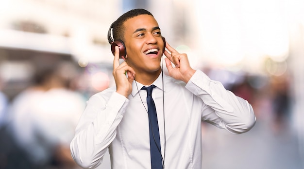 Young afro american businessman listening to music with headphones in the city