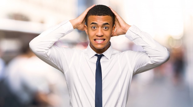 Young afro american businessman takes hands on head because has migraine in the city