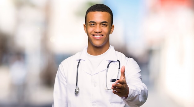 Young afro american man doctor shaking hands for closing a good deal at outdoors