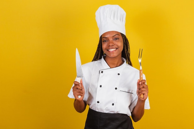 Young afro brazilian woman chef cook holding knife and fork for barbecue getting ready to cook