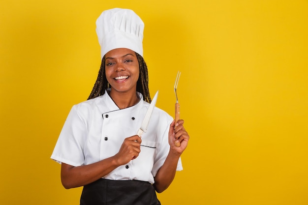 Young afro brazilian woman chef cook holding knife and fork for barbecue getting ready to cook