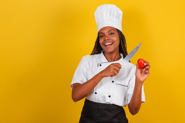 Young afro brazilian woman chef cook holding knife and tomato