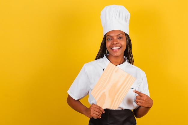 Young afro brazilian woman cook holding wooden board for gastronomy