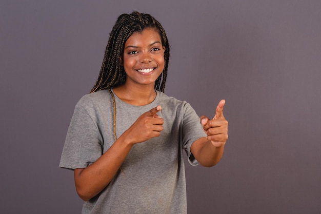 Young afro brazilian woman pointing something far away with fingers advising pointing direction