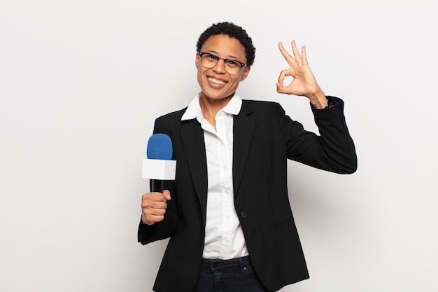 Young afro woman feeling happy, relaxed and satisfied, showing approval with okay gesture, smiling