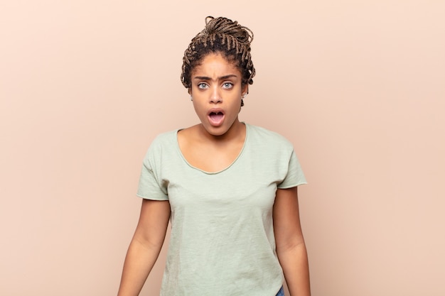 young afro woman looking shocked, angry, annoyed or disappointed, open mouthed and furious