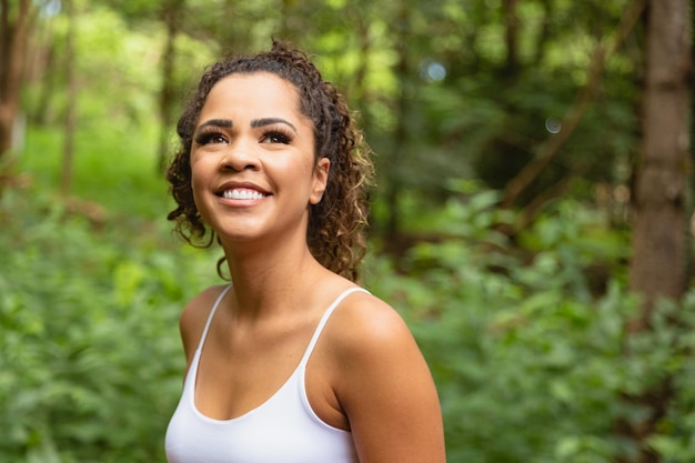 Young afro woman in park smiling at camera.