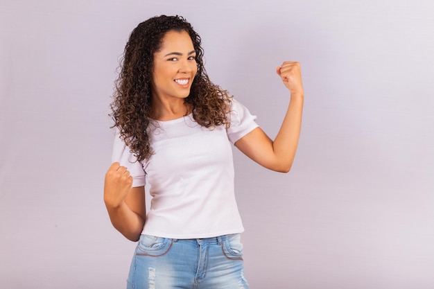 Young afro woman who wins competition screams and celebrates isolated on white background.