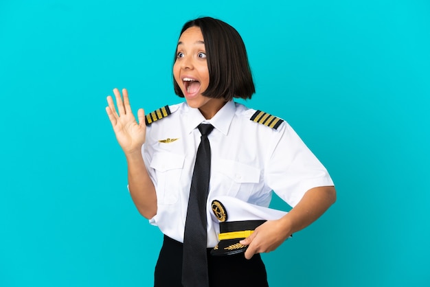 Young airplane pilot over isolated blue background with surprise facial expression