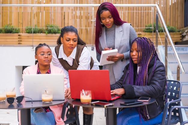 Young and alternative businesswomen of black ethnicity. In a team-building meeting, in a cafeteria with laptops