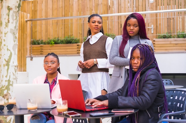 Young and alternative businesswomen of black ethnicity. In a teamwork meeting, posing looking at the camera