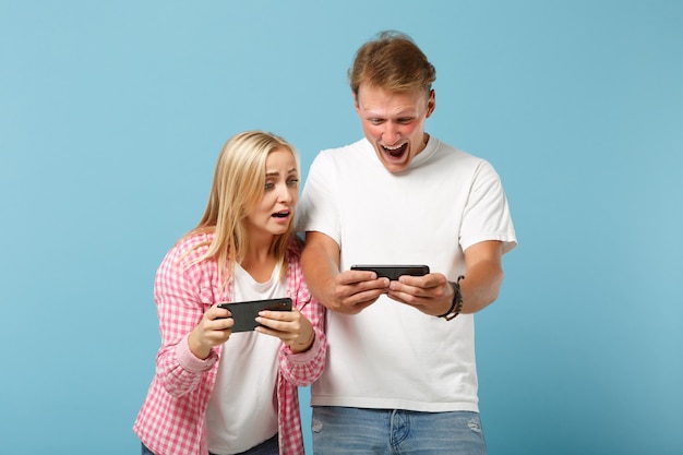 Young amazed couple two friends man and woman  in white pink empty t-shirts posing 