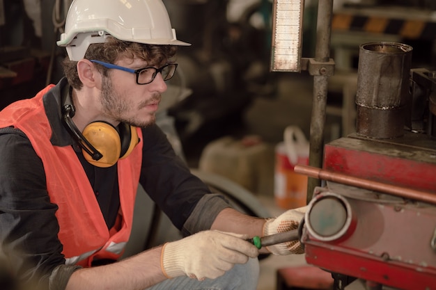 Young american industry skilled manual worker working as technician engineer machine fix repair maintenance in factory.