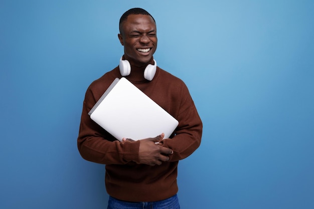 Young american student studying offline with laptop and headphones on background with copy space