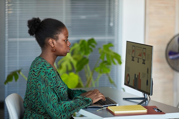 Young analyst or creative designer looking through graphic information on computer screen while sitt