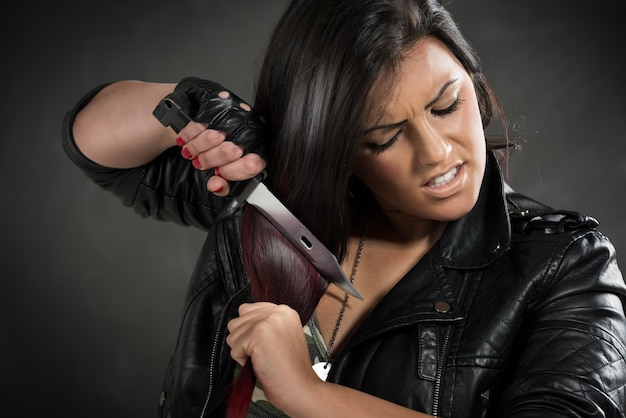 Young anger military woman holding bayonet and wants to cut hair