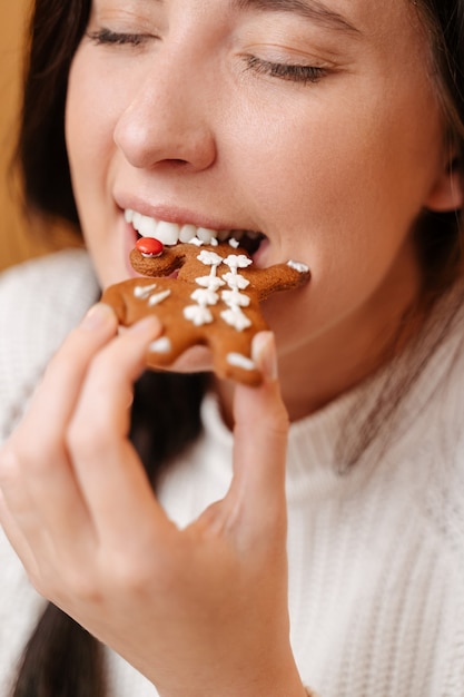 Young appetizing woman takes a bite of traditional christmas gingerbread cookie