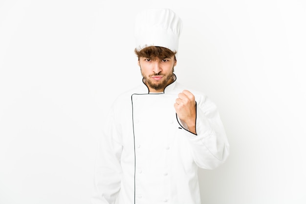 Young arab cook man showing fist to camera, aggressive facial expression.