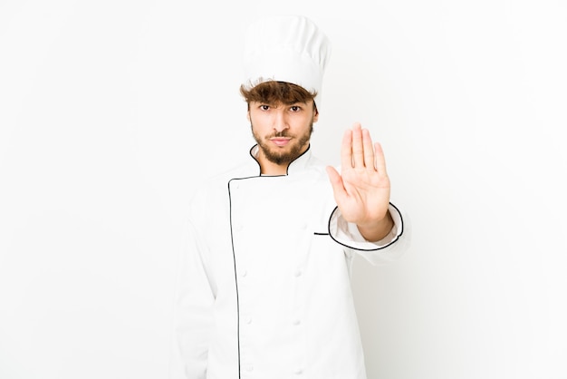 Young arab cook man standing with outstretched hand showing stop sign, preventing you.