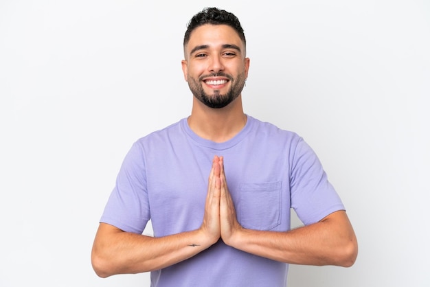 Young Arab handsome man isolated on white background keeps palm together Person asks for something