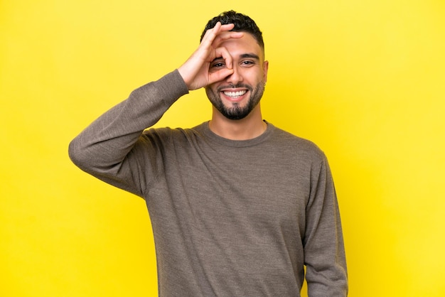 Young Arab handsome man isolated on yellow background showing ok sign with fingers